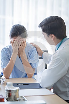 A doctor takes care of a sick patient woman with sadness and unhappiness at the hospital or medical clinic