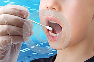 Doctor takes a cotton bud from childÃ¢â¬â¢s mouth to analyze the saliva, mucous membrane for DNA tests, COVID-19, to determine photo