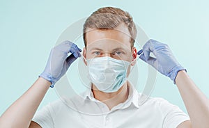 Doctor takes off the medical mask in clinic on light blue background. Healthy concept