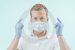 Doctor takes off the medical mask in clinic on light blue background. Healthy concept