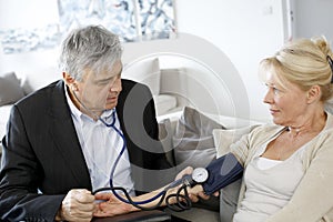 Doctor taking blood pressure to elderly woman