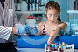 Doctor taking blood sample test of a girl in the clinic