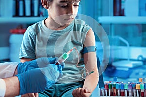 Technician making blood tests on a young boy in the laboratory of blood extractions