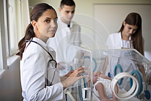 Doctor taking care of newborn baby in incubator