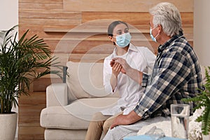 Doctor taking care of senior man with mask at nursing home