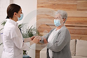 Doctor taking care of senior woman with mask at nursing home