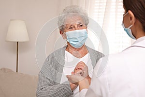 Doctor taking care of senior woman with mask at nursing home