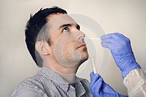 Doctor taking nasal mucus test sample from male nose performing respiratory virus testing procedure. Checking the nasal