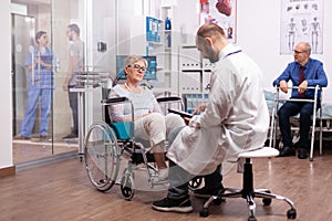 Doctor taking notes on clipboard discussing with invalid woman