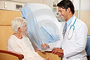 Doctor Taking Notes From Senior Female Patient Seated In Chair