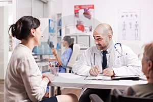 Doctor talking with daughter of senior patient photo