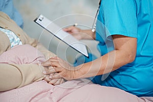 Doctor talking about diagnosis and note on clipboard with Asian senior or elderly old lady woman while lying on bed in nursing hos