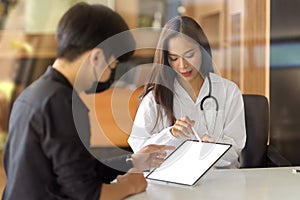 Doctor talking with male patient, discussing medical treatment plans on a tablet