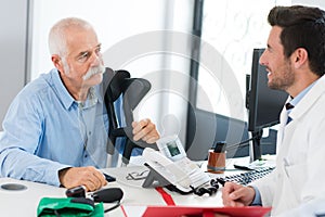 Doctor talking to old man with crutches