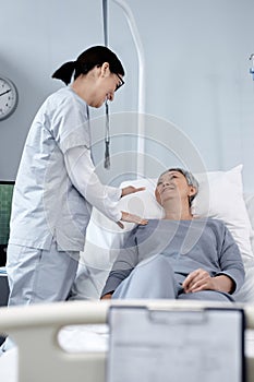 Doctor talking to old woman in ward