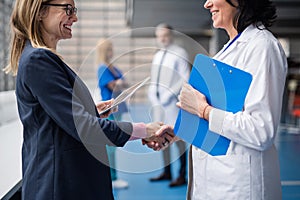 Doctor talking to pharmaceutical sales representative, shaking hands.