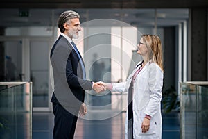 Doctor talking to pharmaceutical sales representative, shaking hands.