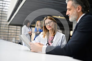 Doctor talking to pharmaceutical sales representative, shaking hands. Hospital manager talking with female doctor.