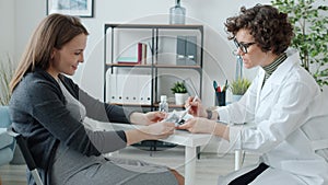 Doctor talking to pregnant patient looking at ultrasound scan image at table in clinic office