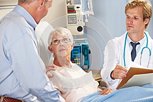 Doctor Talking To Senior Couple On Ward