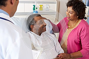 Doctor Talking To Senior Couple On Ward