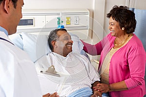 Doctor Talking To Senior Couple On Ward