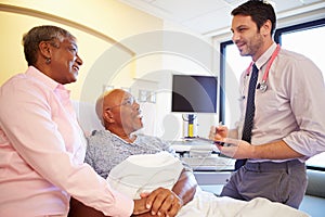 Doctor Talking To Senior Couple On Ward