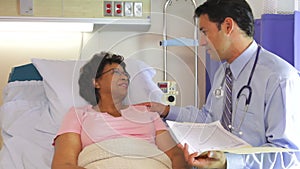 Doctor Talking To Senior Female Patient In Hospital Bed