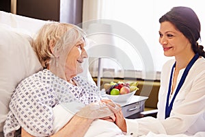 Doctor Talking To Senior Female Patient In Hospital Bed