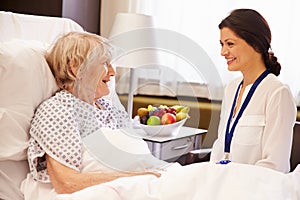 Doctor Talking To Senior Female Patient In Hospital Bed