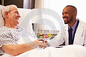 Doctor Talking To Senior Male Patient In Hospital Bed