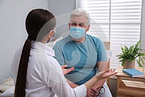 Doctor talking to senior man with mask at nursing home