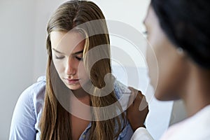 Doctor Talking To Unhappy Teenage Patient In Exam Room