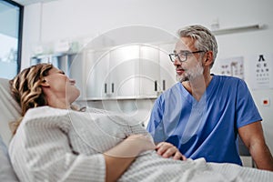 Doctor talking with worried patient, emotional support before surgery. Friendly male doctor reassuring the patient.