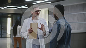 Doctor talks to African American man in clinic lobby