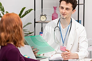 A doctor talks to a redheaded patient with a smile on his face. An adult woman in a doctor's office