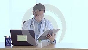 Doctor talks about treatment of patient through an online conference call on a laptop.Doctor filling medical history sheet