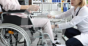 Doctor taps with hammer on nerve endings of leg of patient in wheelchair