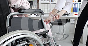 Doctor taps knee of patient in wheelchair with hammer