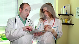 Doctor team man and woman discussing looking at tablet computer and hand shake