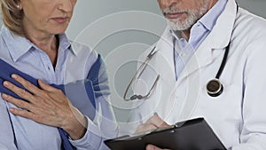 Doctor telling his female patient unfavorable news, breast cancer awareness