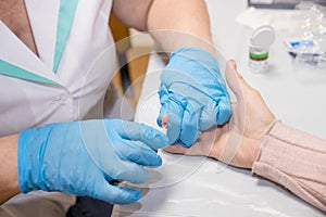 Doctor testing a patients glucose level after pricking his finger to draw a drop of blood and then using a digital