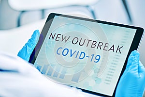 Doctor and text covid-19 new outbreak in a tablet