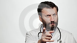 Doctor threatens with his finger. Serious frowning man doctor on white background looking at camera and points