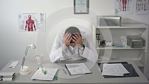 Doctor tired and holding his head at medical cabinet