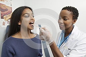 Doctor With Tongue Depressor Examining Patient photo