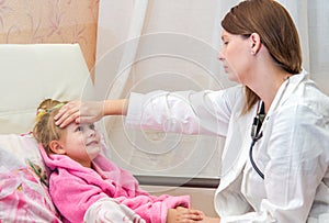 Doctor touches the forehead a little sick girl