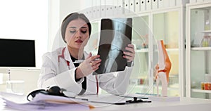 Doctor traumatologist examining xray of knee joint near anatomical model 4k movie slow motion