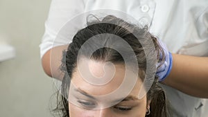 Doctor trichologist massaging woman`s head skin after mesotherapy injections.