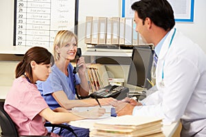 Doctor With Two Nurses Working At Nurses Station